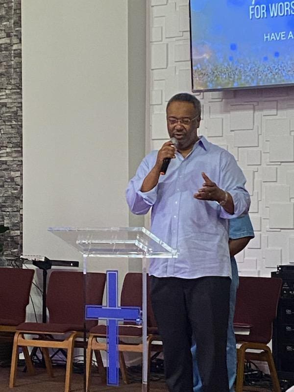 Pastor speaking into microphone at clear pulpit