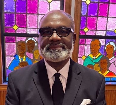 Man in suit and tie before stained glass