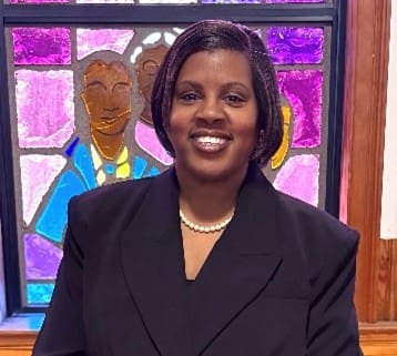 Smiling person in front of stained-glass window