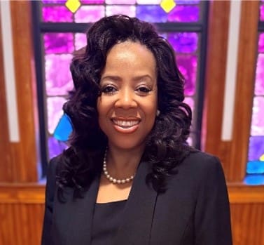 Smiling woman in black suit before stained glass