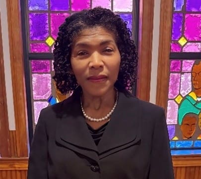 Woman wearing pearls before stained-glass window
