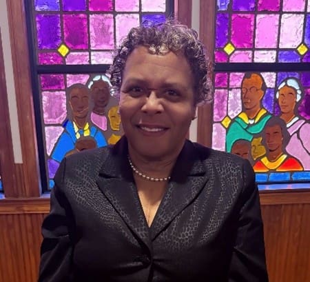 Smiling person in front of stained glass window