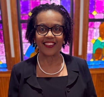 Smiling person wearing glasses and pearl necklace