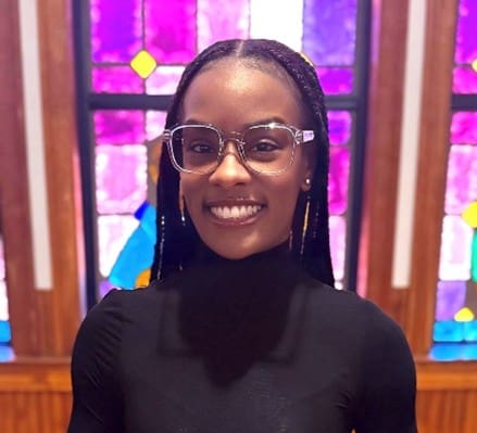 Smiling woman with glasses by stained glass