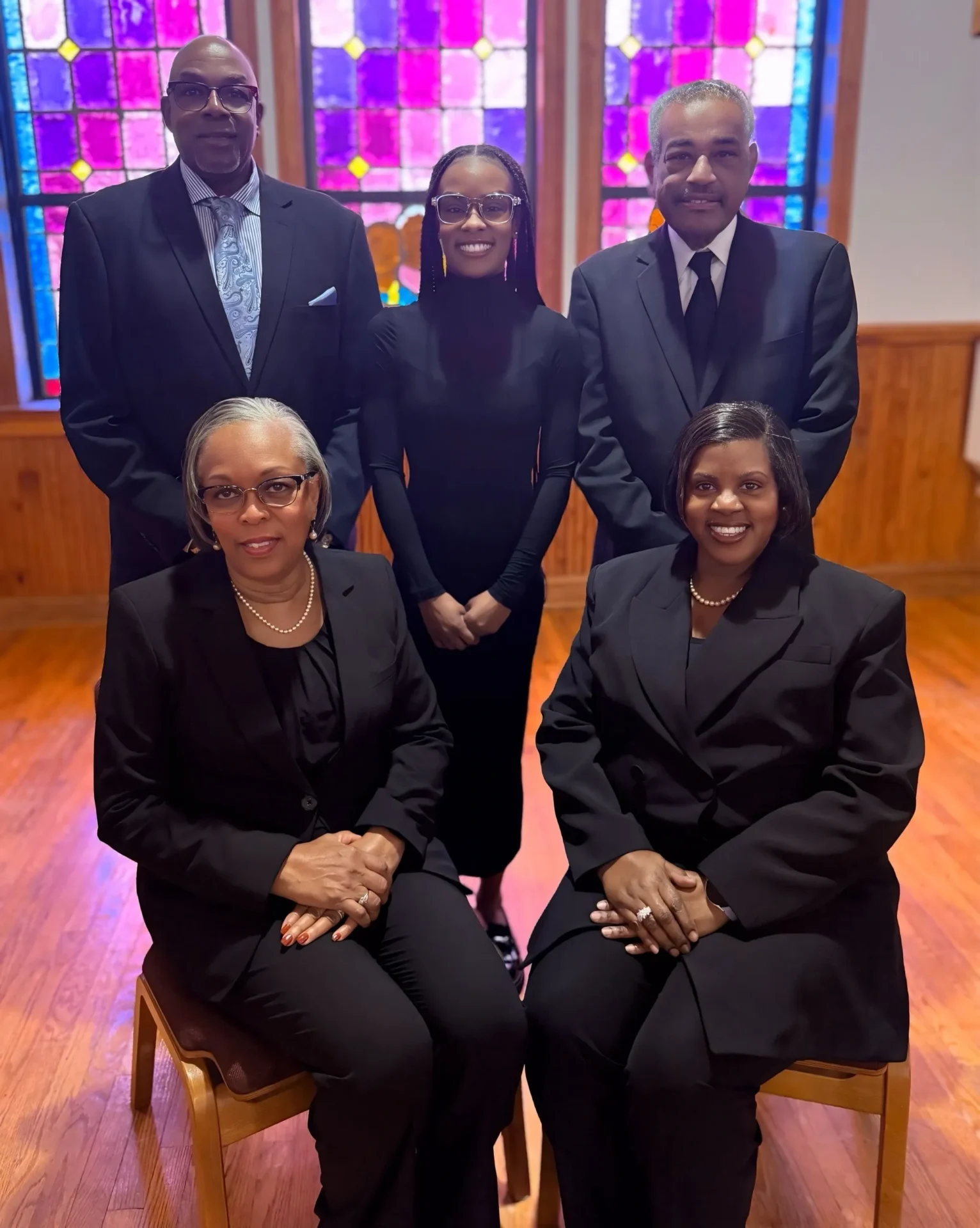 Five people in black formal attire posing