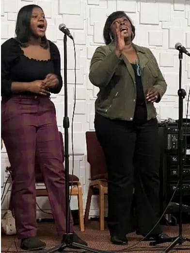 Two women singing into microphones