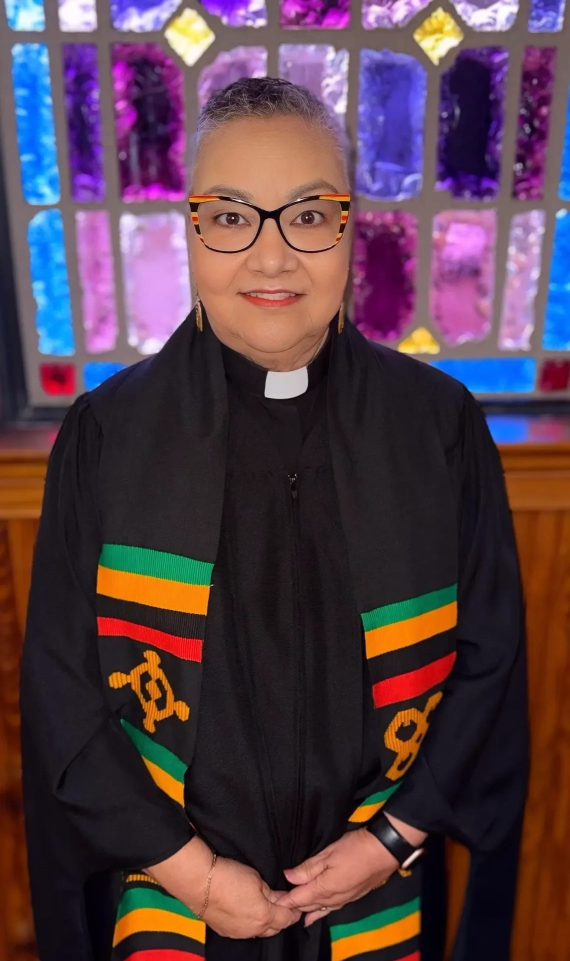 Clergy wearing colorful stole before stained glass
